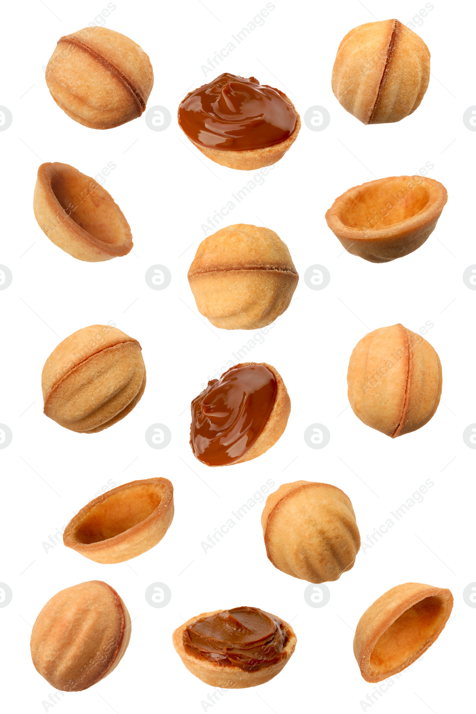 Image of Many delicious nut shaped cookies with caramelized condensed milk falling on white background