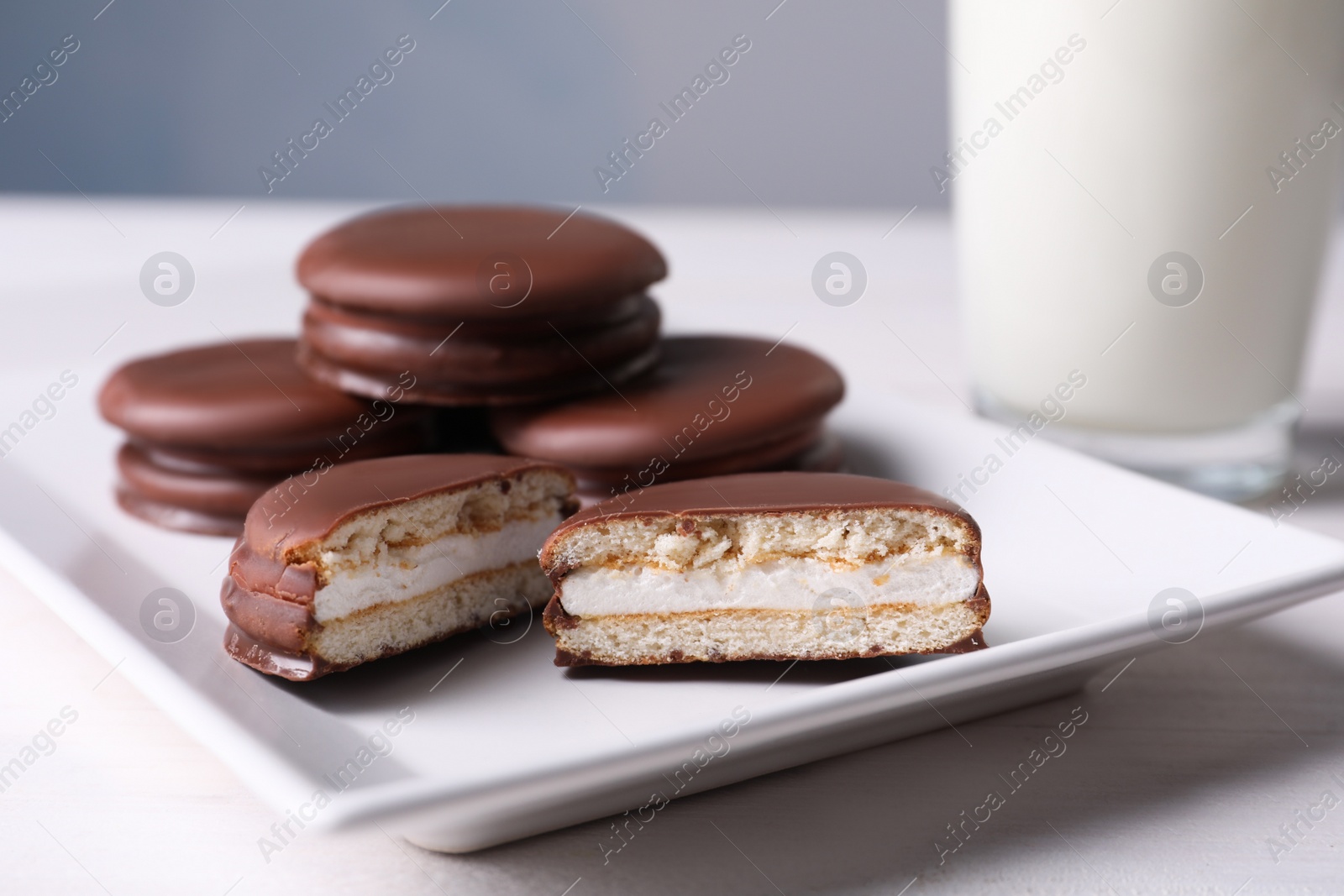 Photo of Tasty choco pies and milk on white wooden table, closeup view