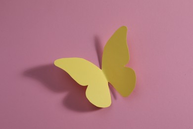 Photo of Yellow paper butterfly on pink background, top view