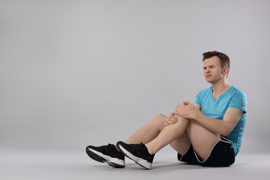 Photo of Man suffering from leg pain on grey background. Space for text