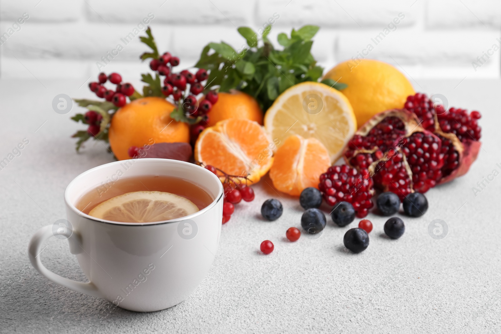 Photo of Cup of delicious immunity boosting tea with ingredients on light grey table