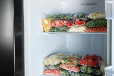 Photo of Plastic bags with different frozen vegetables in refrigerator
