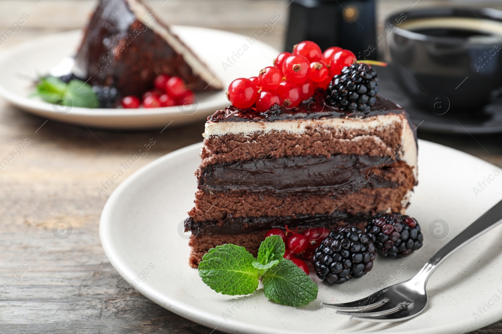 Photo of Tasty chocolate cake with berries on wooden table, closeup