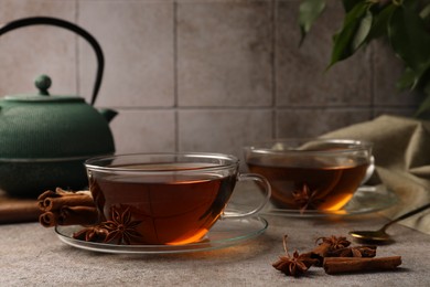 Photo of Aromatic tea with anise stars and cinnamon sticks on light grey table. Space for text
