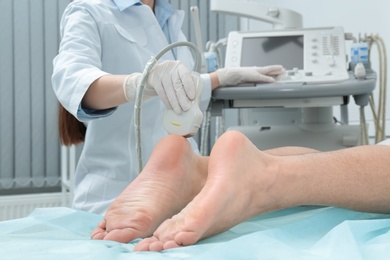 Doctor conducting ultrasound examination of patient's foot in clinic