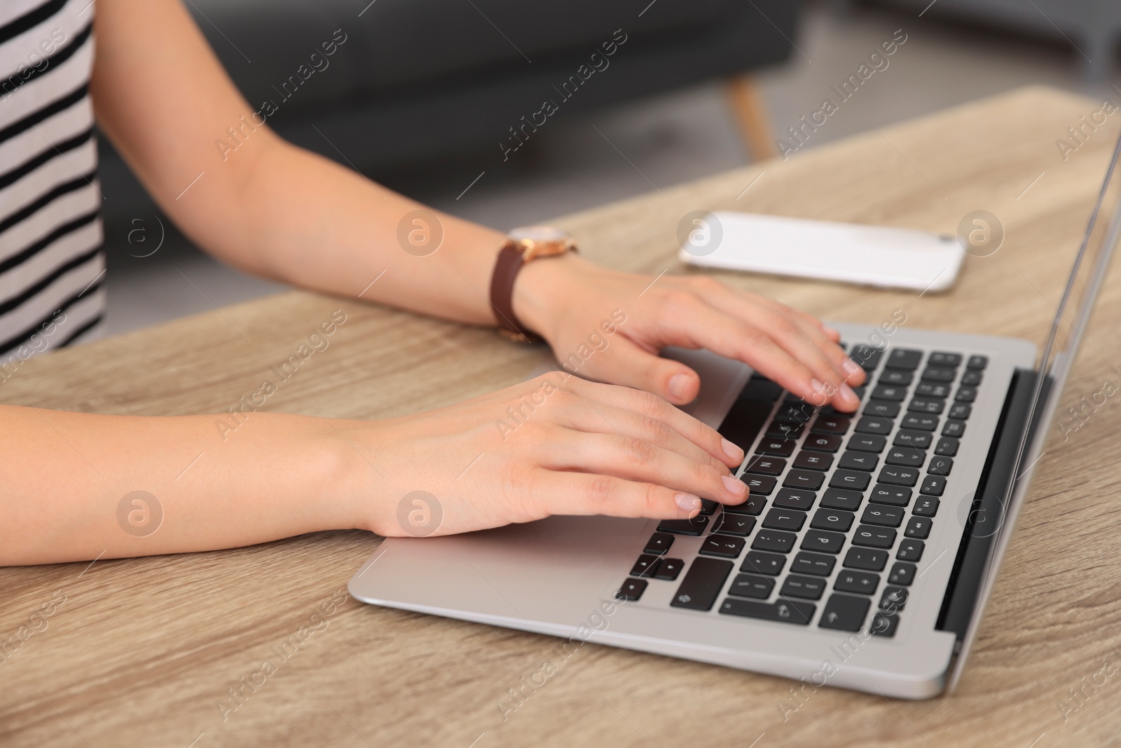 Photo of Woman working with laptop at wooden table indoors, closeup