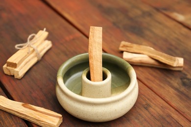 Photo of Palo Santo sticks and holder on wooden table