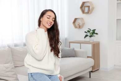 Beautiful young woman in stylish warm sweater at home, space for text