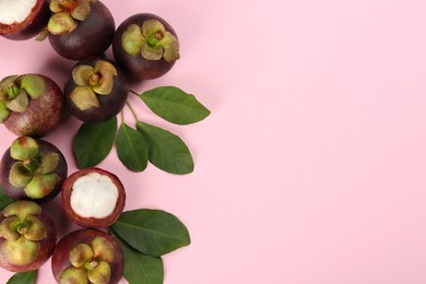 Fresh ripe mangosteen fruits with green leaves on pink background, flat lay. Space for text