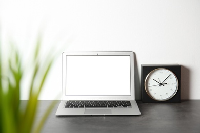 Photo of Modern laptop monitor on table against white wall. Mock up with space for text