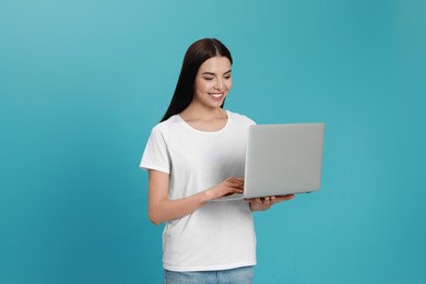 Photo of Young woman with modern laptop on light blue background