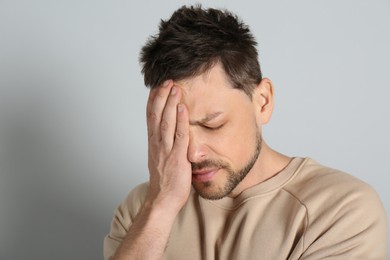 Photo of Man suffering from terrible migraine on light grey background