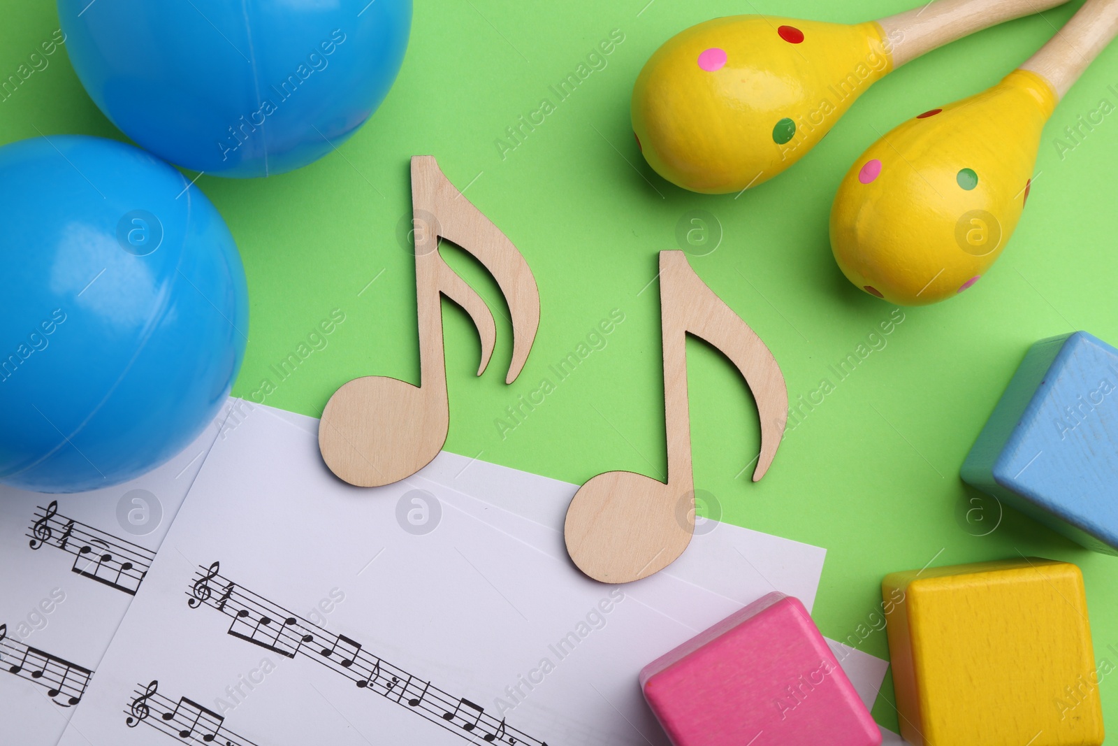 Photo of Tools for creating baby songs. Flat lay composition with wooden notes and maracas on green background