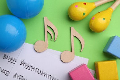 Photo of Tools for creating baby songs. Flat lay composition with wooden notes and maracas on green background