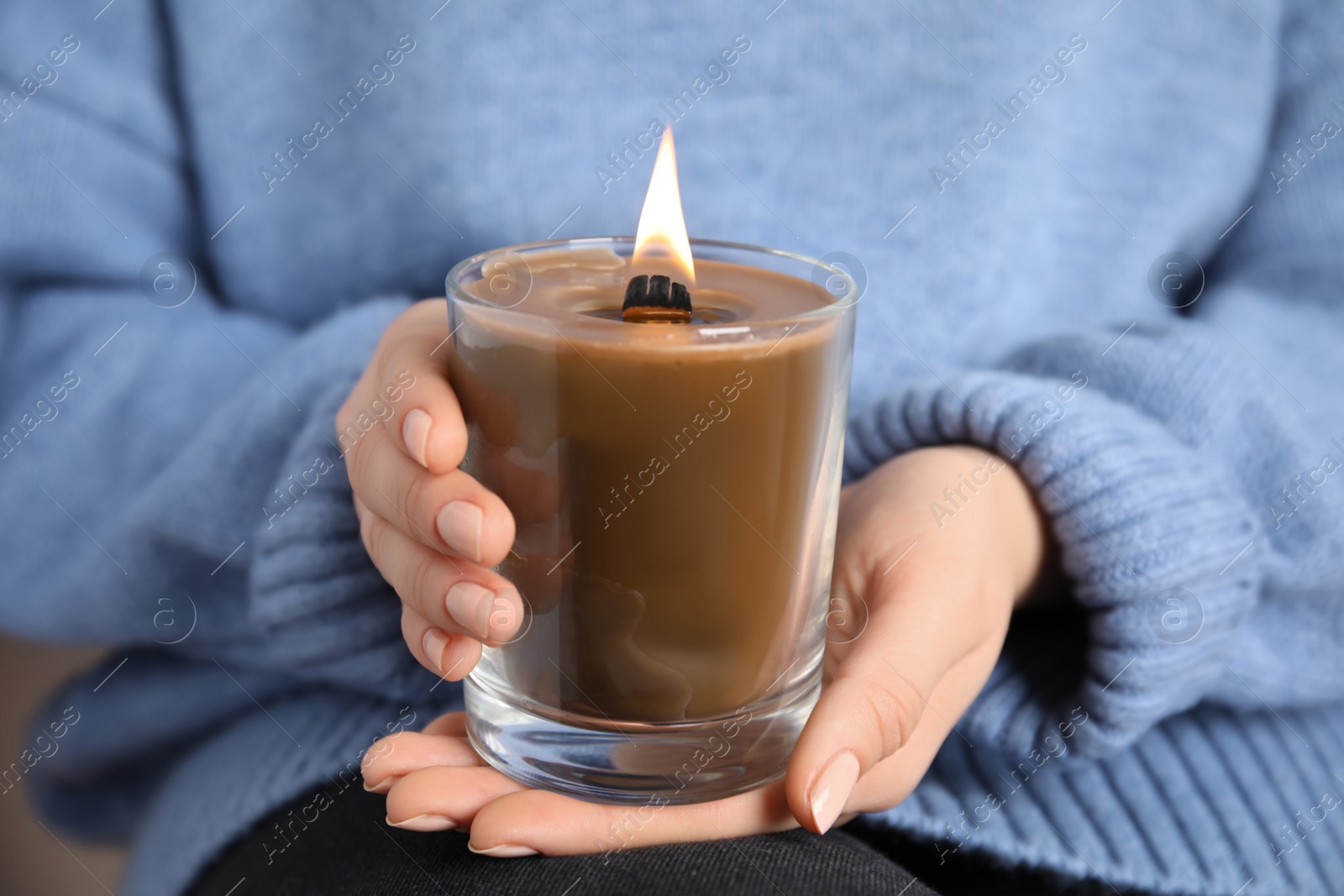 Photo of Woman holding burning candle with wooden wick, closeup