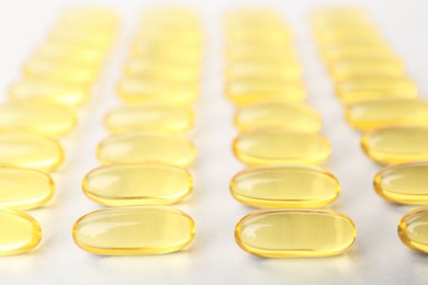 Photo of Yellow vitamin capsules on white background, closeup