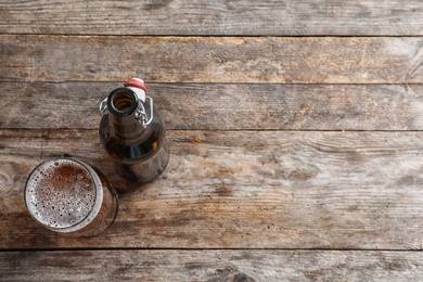 Photo of Bottle and glass with tasty cold beer on wooden background