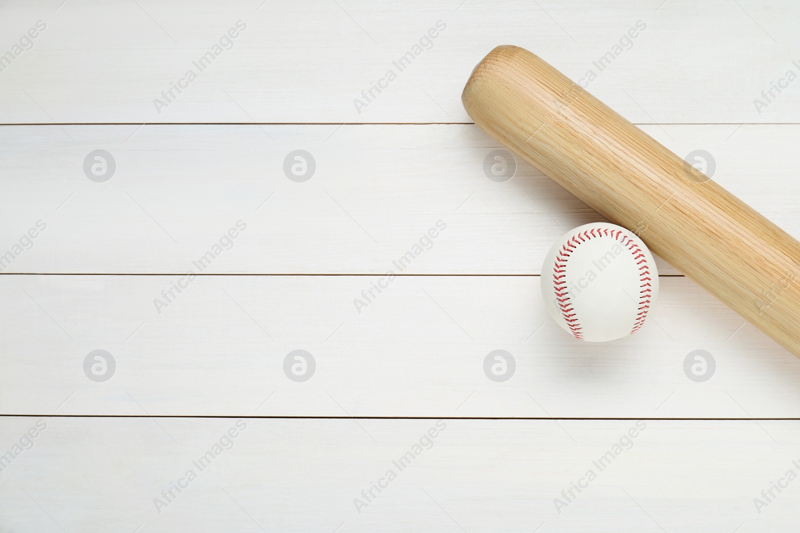 Photo of Baseball bat and ball on white wooden table, top view with space for text. Sports equipment