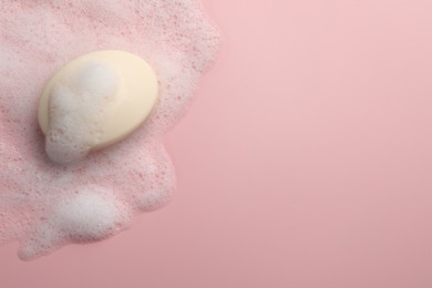 Photo of Soap with fluffy foam on pink background, top view. Space for text