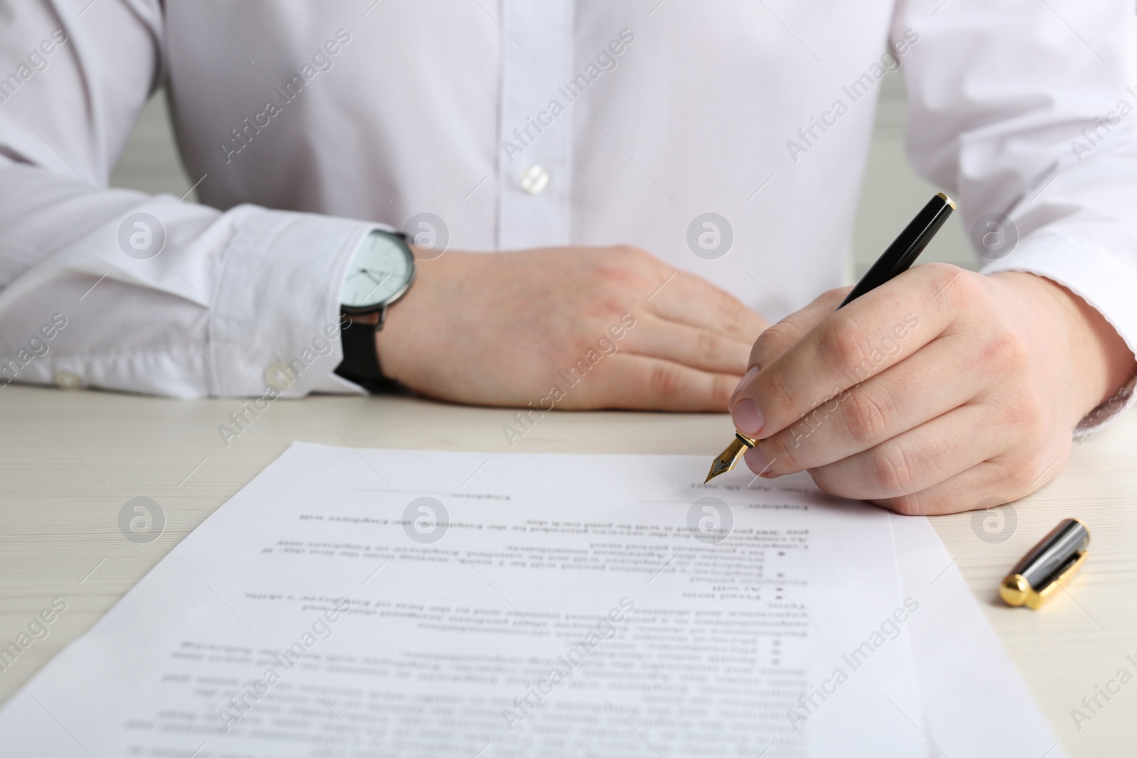 Photo of Notary signing document at wooden table, closeup