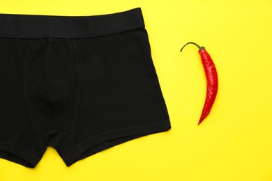 Photo of Men's underwear and chili pepper on yellow background, flat lay. Potency problem concept