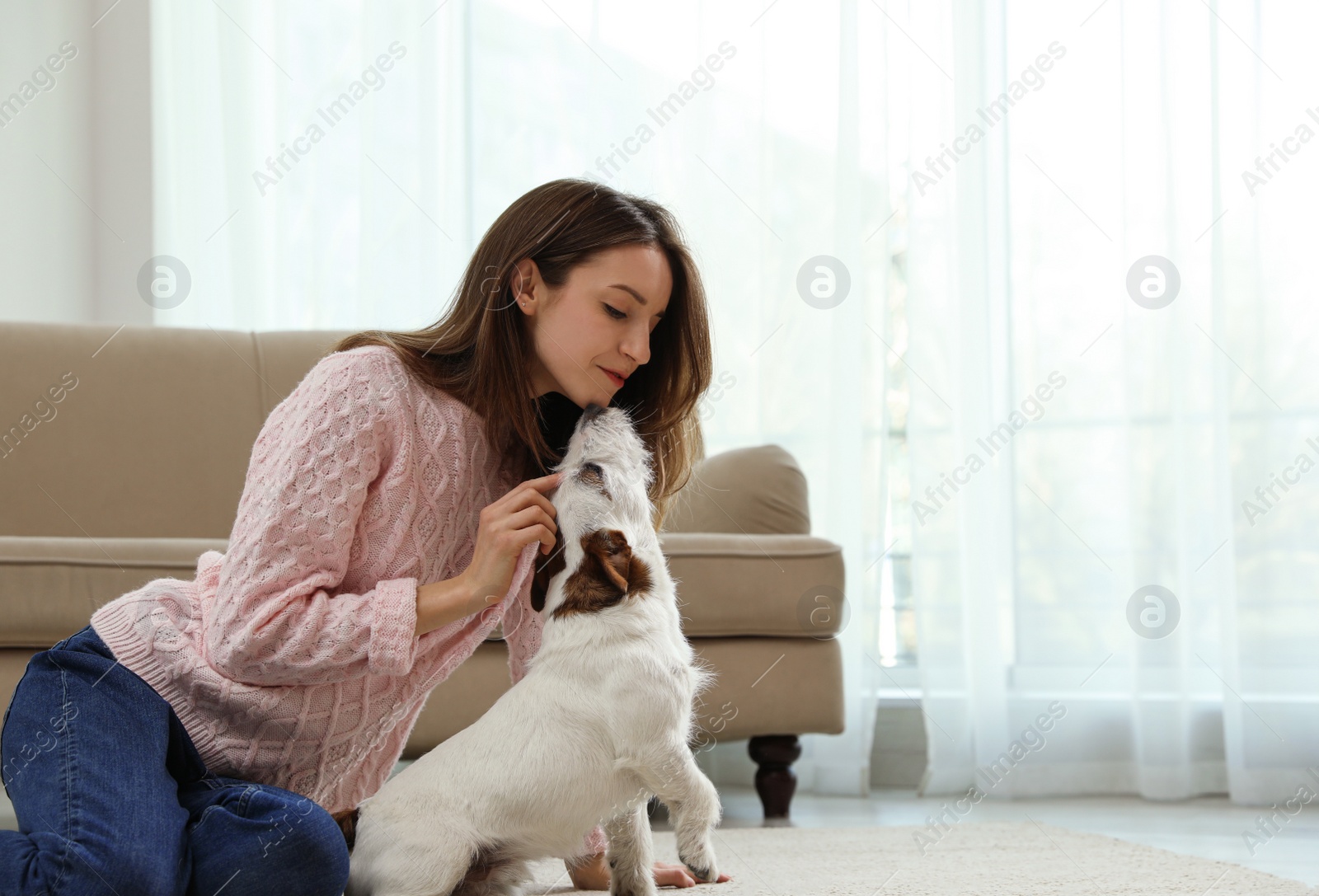Photo of Young woman with her cute Jack Russell Terrier at home, space for text. Lovely pet