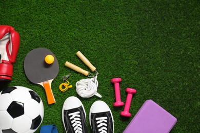 Photo of Different sports equipment on green grass, flat lay. Space for text