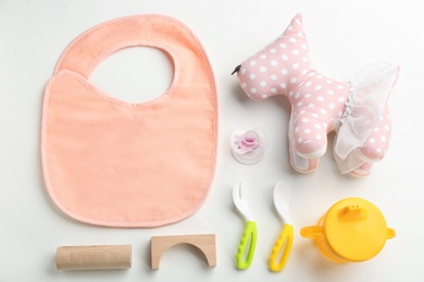 Flat lay composition with baby accessories and tableware for food on light background
