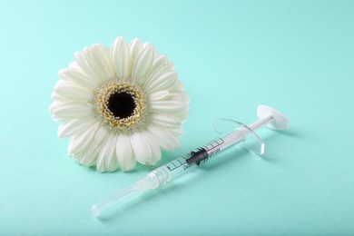 Photo of Cosmetology. Medical syringe and gerbera flower on turquoise background