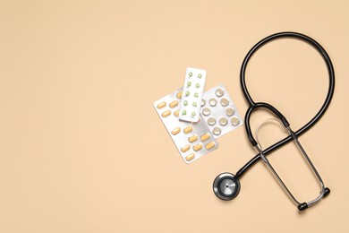 Stethoscope and pills on beige background, flat lay. Space for text