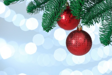 Photo of Beautiful holiday baubles hanging on Christmas tree against blurred lights, closeup. Space for text