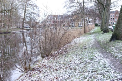 Photo of Picturesque view of water canal, trees and buildings in city on winter day