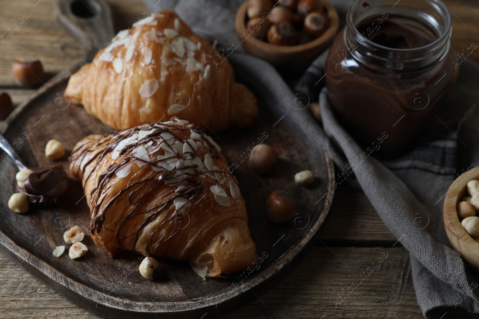 Photo of Delicious croissants with chocolate and nuts on wooden table