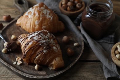 Delicious croissants with chocolate and nuts on wooden table