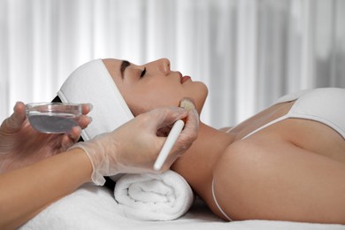 Young woman during face peeling procedure in salon