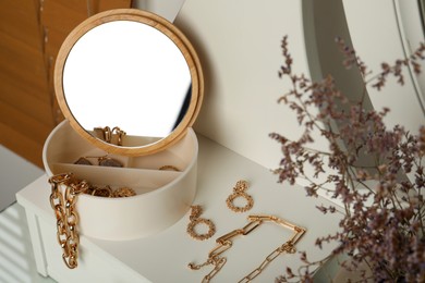 Photo of Jewelry box with mirror and stylish golden bijouterie on table