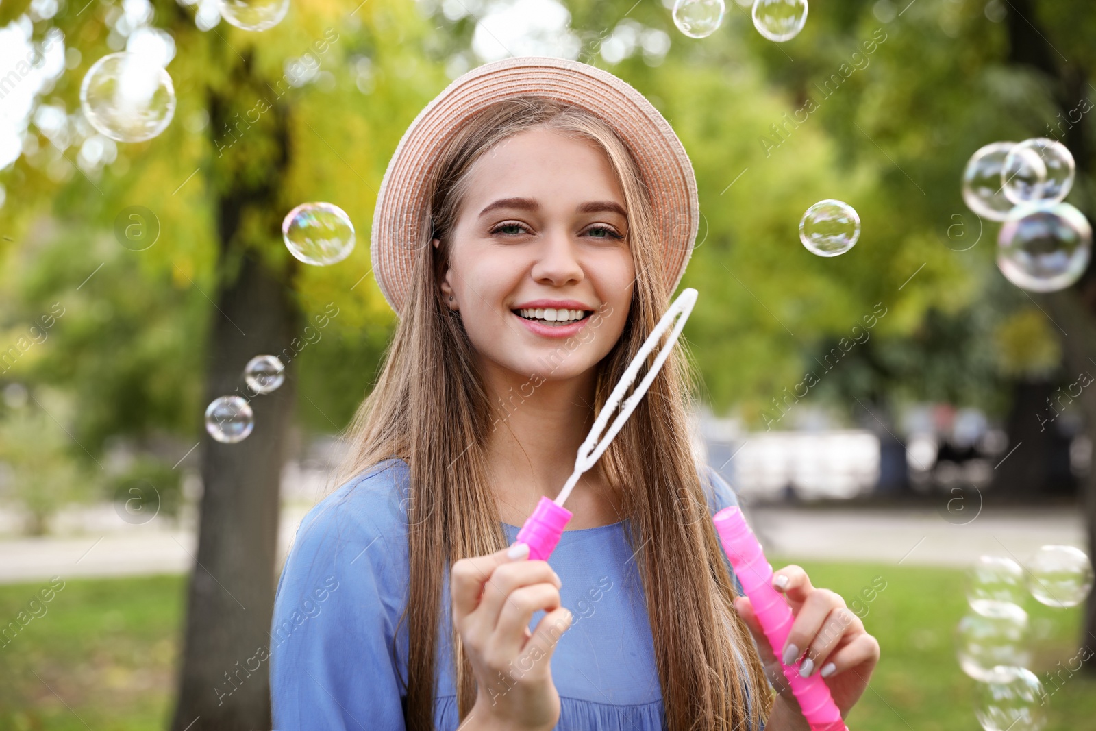 Photo of Young woman blowing soap bubbles in park