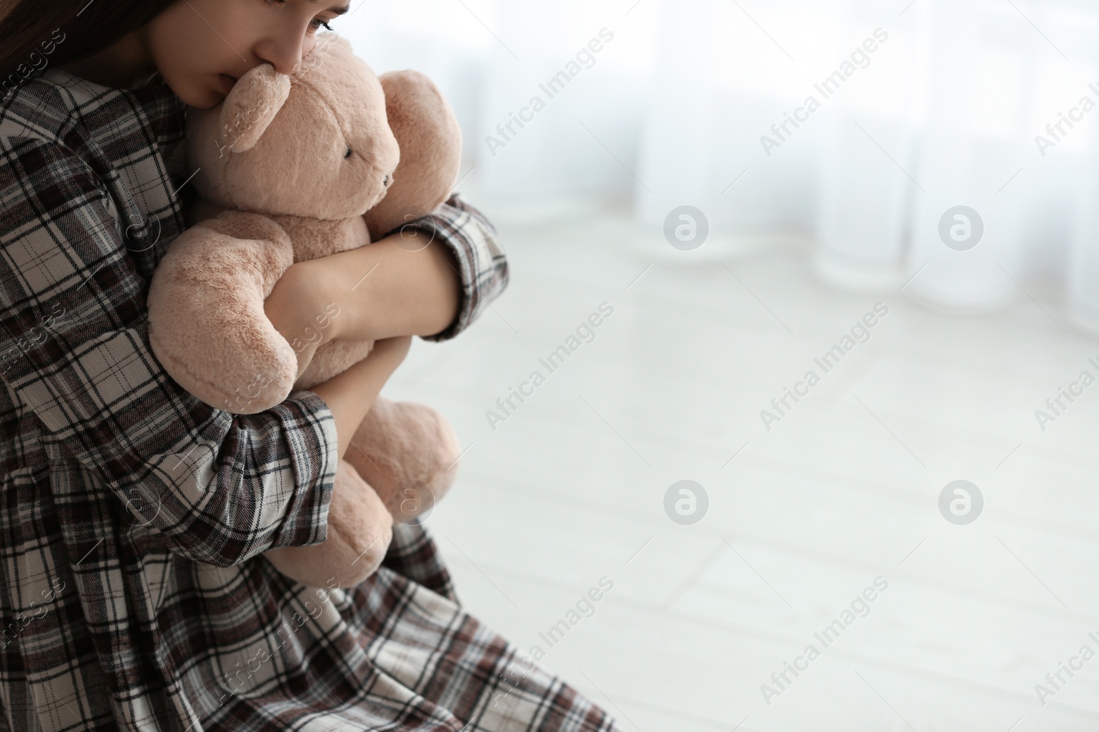 Photo of Upset girl with toy indoors, closeup. Space for text