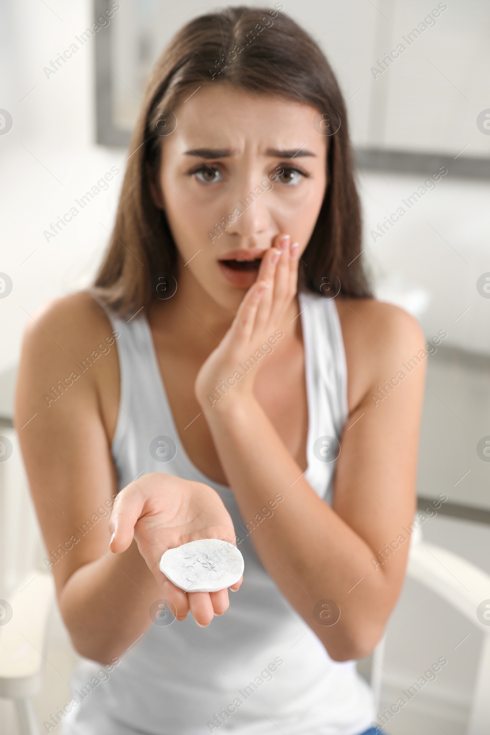 Photo of Young woman holding cotton pad with fallen eyelashes indoors