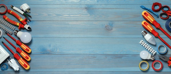 Photo of Frame of electrician's tools and accessories on light blue wooden table, flat lay. Space for text