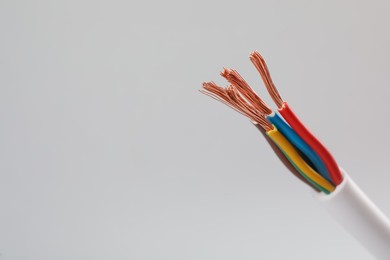 Cable with stripped wires on light background, closeup. Space for text