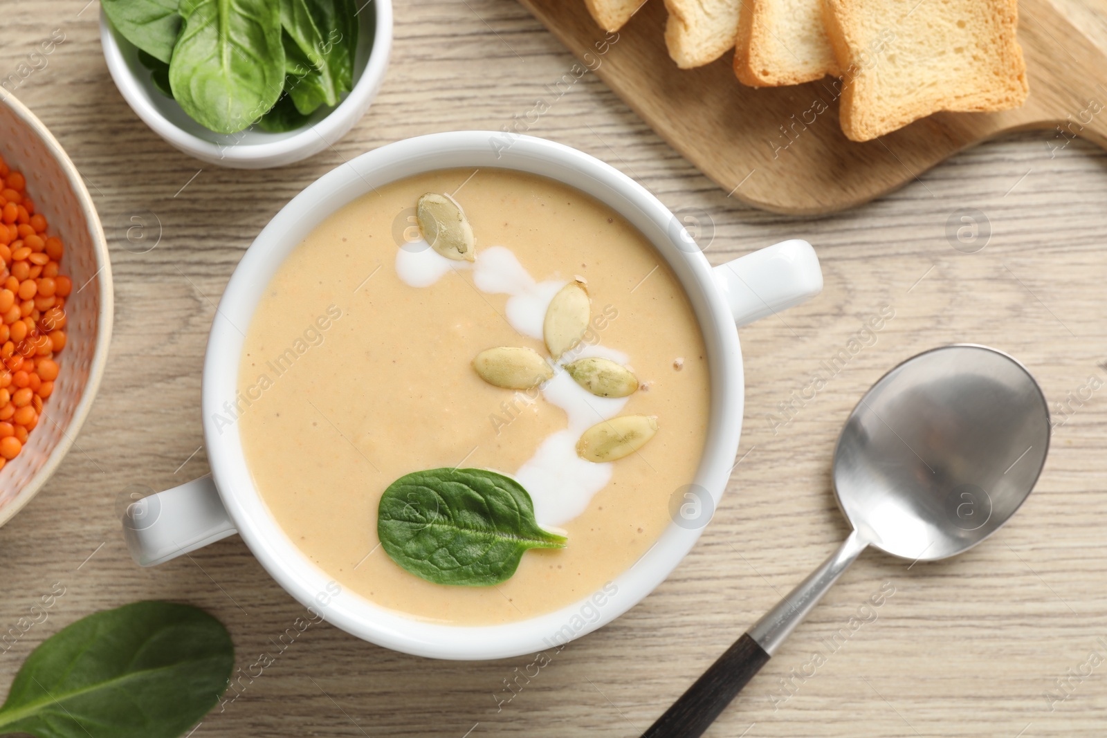 Photo of Healthy cream soup high in vegetable fats served on wooden table, flat lay