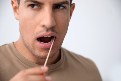 Photo of Man taking sample for DNA test on light background, closeup