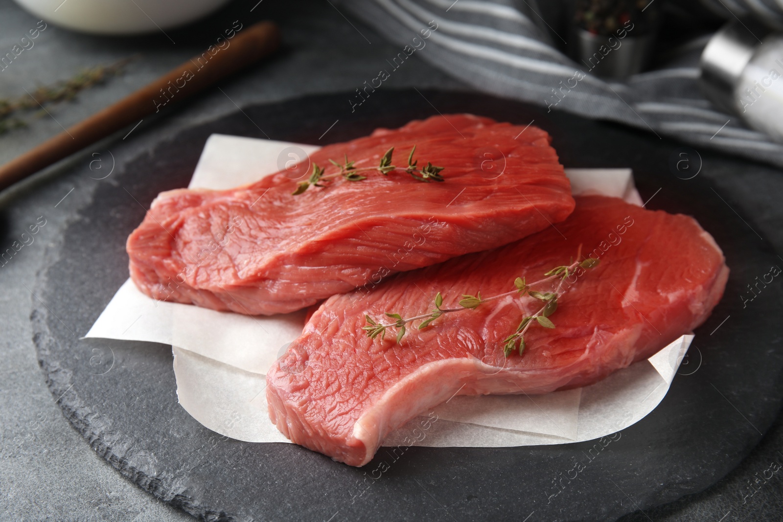 Photo of Fresh raw beef cut with thyme on grey table, closeup