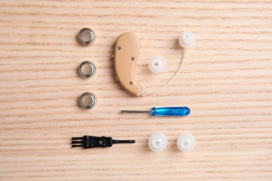 Photo of Flat lay composition with hearing aid and accessories on wooden background