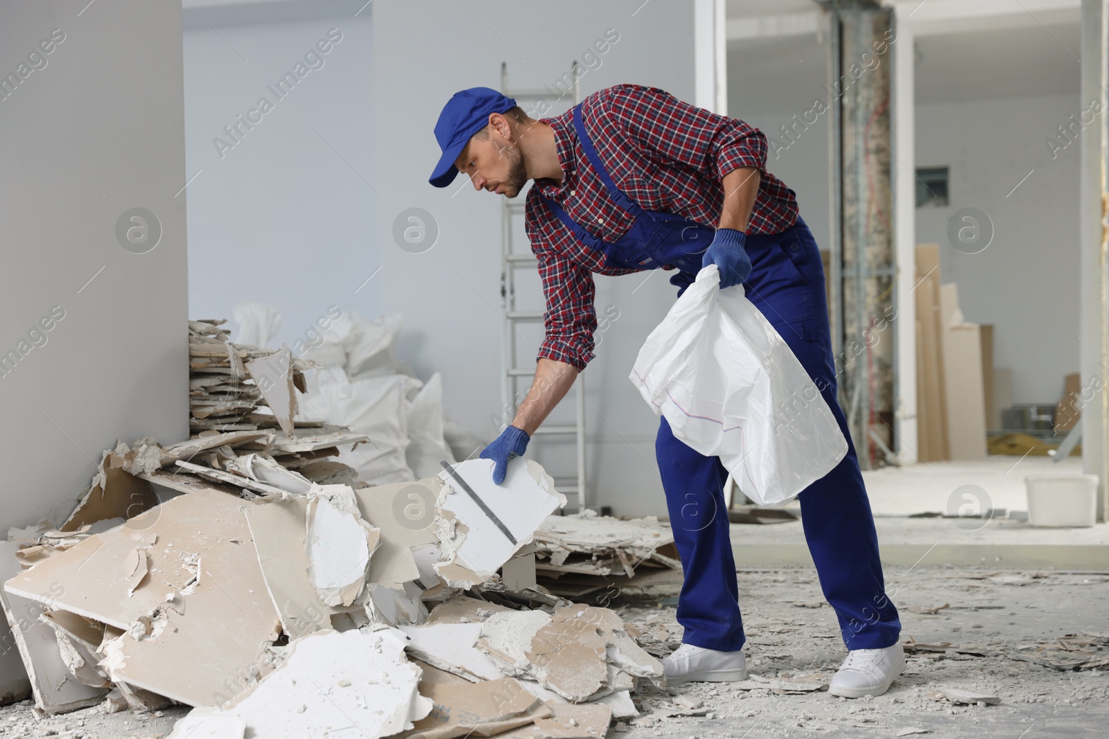 Photo of Construction worker with used building materials in room prepared for renovation