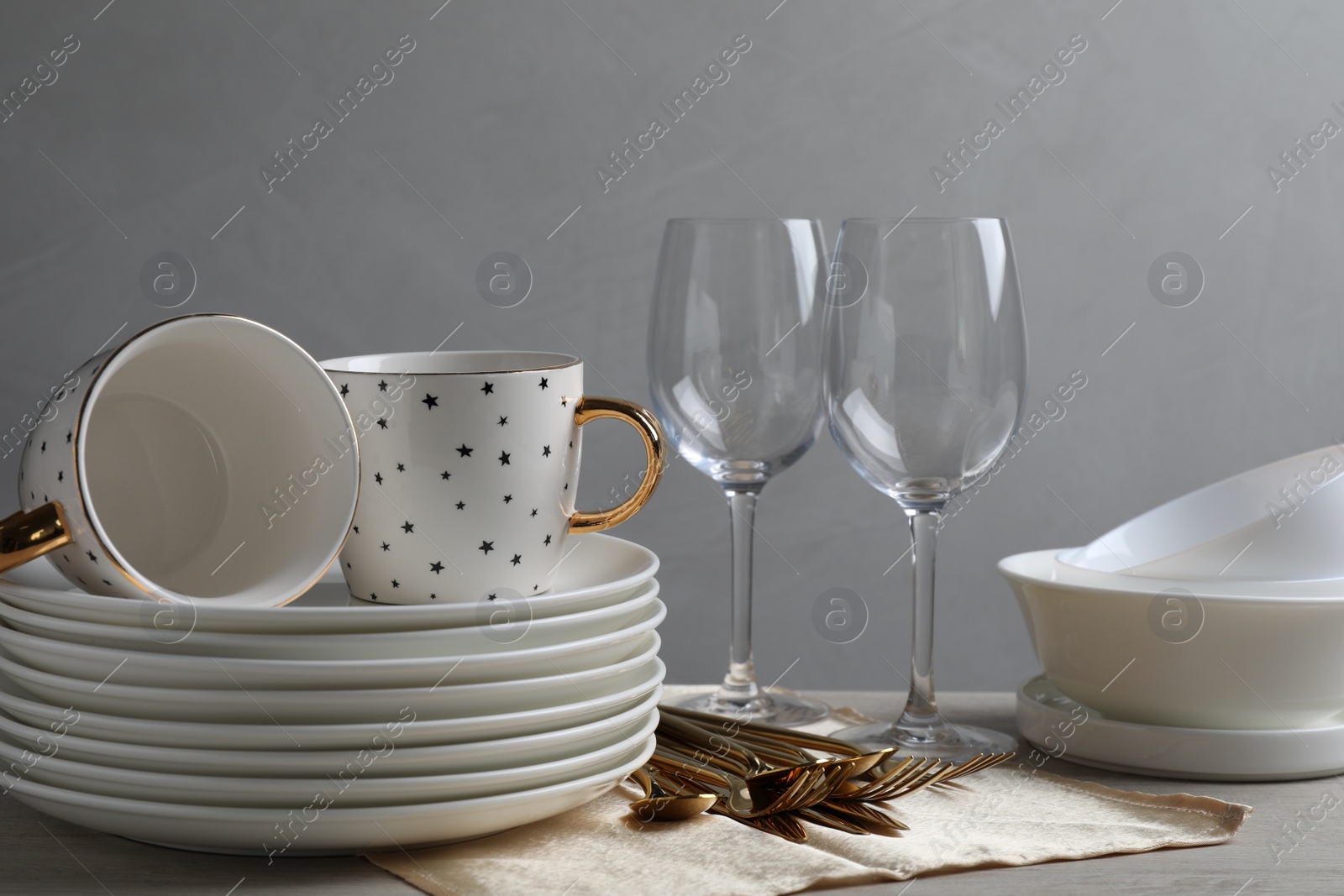 Photo of Set of clean dishware, glasses and cutlery on wooden table