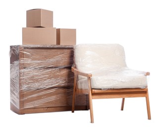 Boxes, armchair and chest of drawers wrapped in stretch film on white background