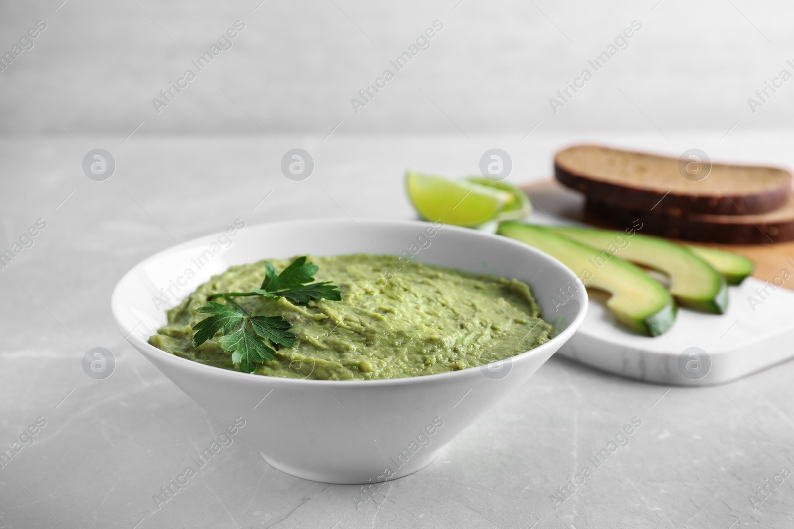 Photo of Bowl with guacamole made of ripe avocados served on light table, space for text