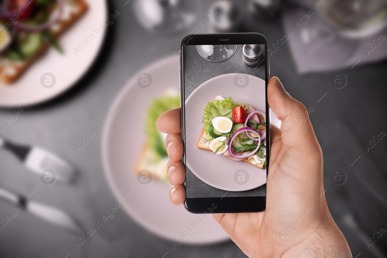 Image of Blogger taking picture of delicious sandwich with ham at table, closeup. Food photography